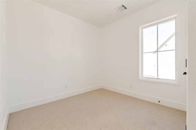 spare room with light colored carpet, visible vents, and baseboards