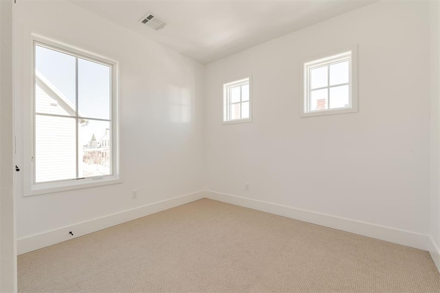 unfurnished room with a healthy amount of sunlight, visible vents, light carpet, and baseboards