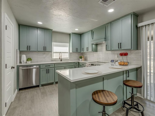 kitchen with sink, appliances with stainless steel finishes, light hardwood / wood-style floors, a kitchen bar, and kitchen peninsula