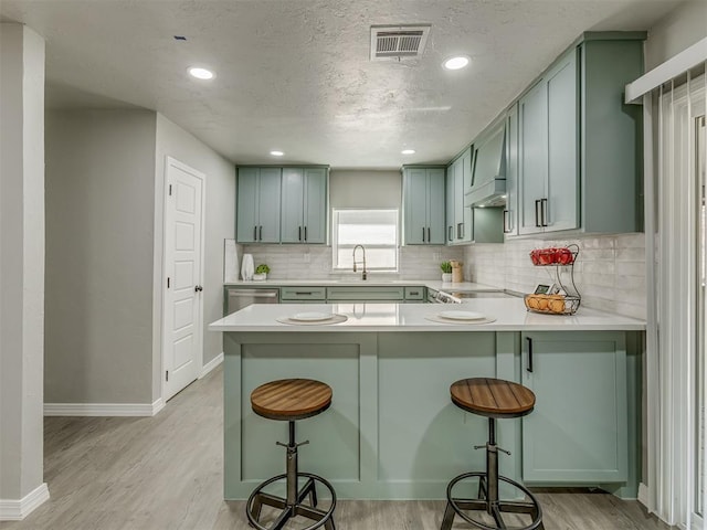 kitchen featuring kitchen peninsula, decorative backsplash, a breakfast bar, and sink