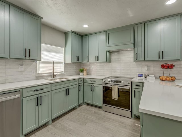 kitchen with green cabinets, sink, light hardwood / wood-style floors, and stainless steel appliances