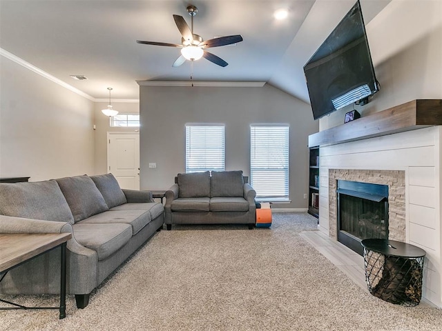 living room with ceiling fan, a stone fireplace, crown molding, vaulted ceiling, and light carpet