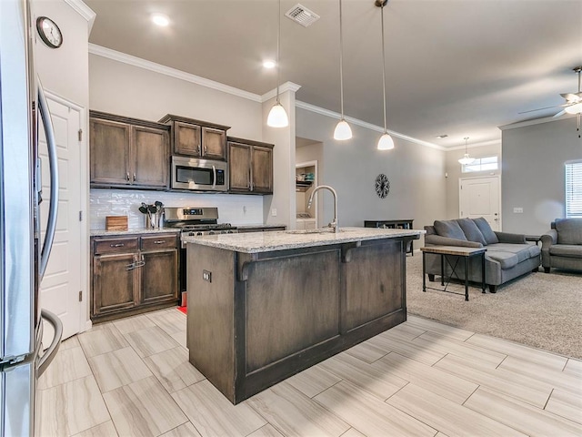 kitchen featuring a breakfast bar, sink, an island with sink, appliances with stainless steel finishes, and decorative light fixtures