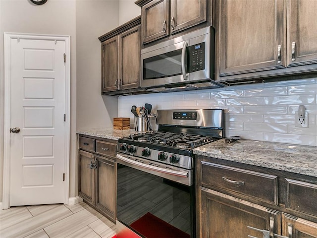 kitchen featuring light stone countertops, appliances with stainless steel finishes, and dark brown cabinetry