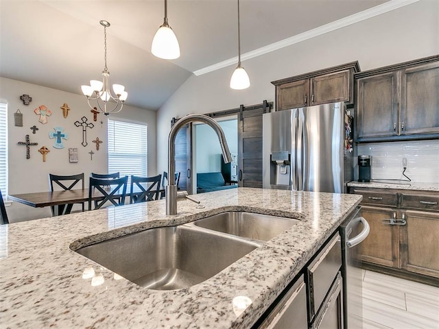 kitchen featuring stainless steel refrigerator with ice dispenser, dark brown cabinetry, sink, pendant lighting, and a barn door