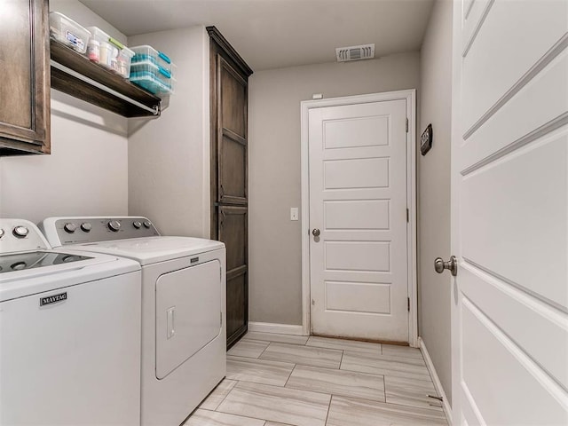 washroom featuring cabinets and washer and clothes dryer