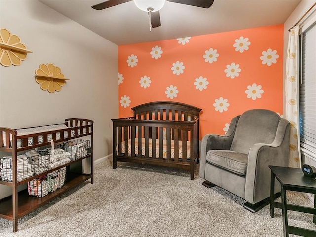 carpeted bedroom with a crib and ceiling fan