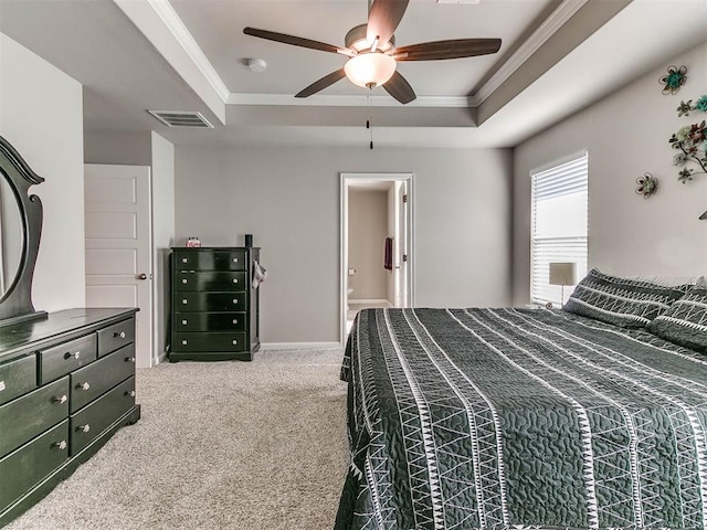 carpeted bedroom featuring a tray ceiling, ensuite bath, ceiling fan, and ornamental molding