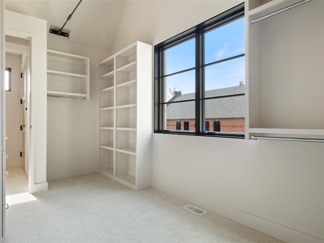 spacious closet with light carpet and vaulted ceiling