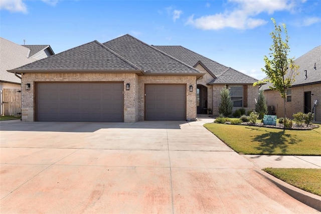 french country inspired facade with a front yard, an attached garage, driveway, and a shingled roof