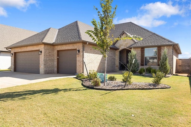 view of front of home with driveway, roof with shingles, a front yard, an attached garage, and brick siding