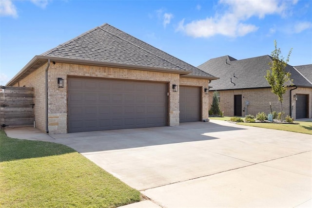 view of front of home featuring brick siding, an attached garage, a shingled roof, a front yard, and driveway