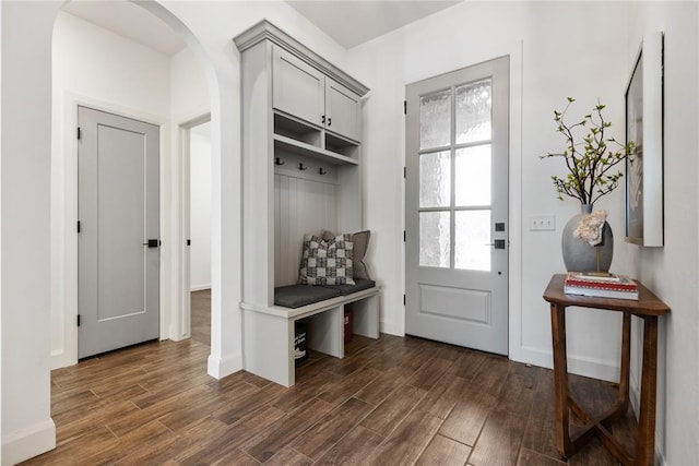 mudroom featuring baseboards, arched walkways, and dark wood-style flooring