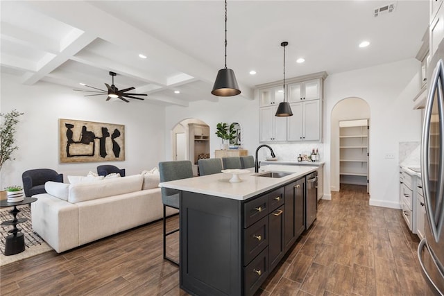 kitchen with visible vents, arched walkways, a sink, dishwasher, and a kitchen bar