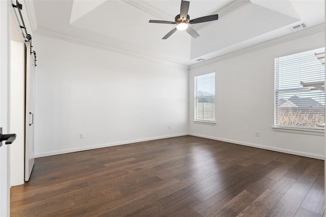 unfurnished room featuring visible vents, a tray ceiling, dark wood-style flooring, ceiling fan, and a barn door