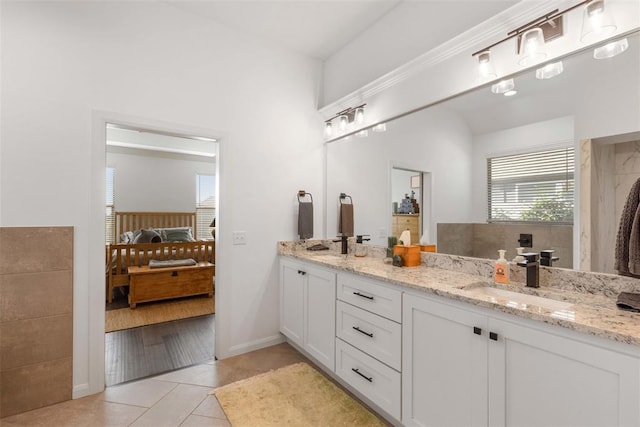 ensuite bathroom with baseboards, double vanity, ensuite bath, a sink, and tile patterned flooring