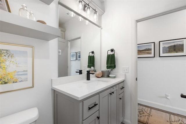 bathroom featuring toilet, vanity, and baseboards