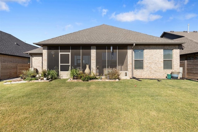 back of property with a lawn, fence, roof with shingles, a sunroom, and brick siding