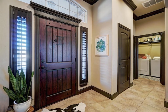 tiled entrance foyer with a healthy amount of sunlight, crown molding, and washing machine and clothes dryer