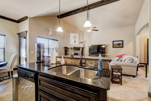 kitchen featuring a kitchen island with sink, dark stone countertops, pendant lighting, stainless steel dishwasher, and sink