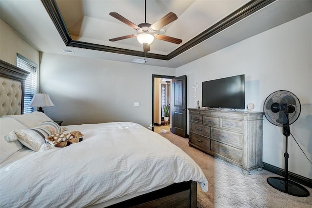 bedroom with ceiling fan, a tray ceiling, ornamental molding, and light carpet