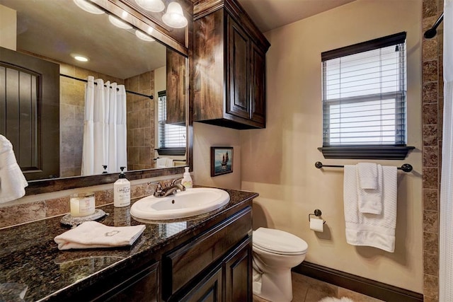 bathroom with toilet, a wealth of natural light, tile patterned floors, and vanity