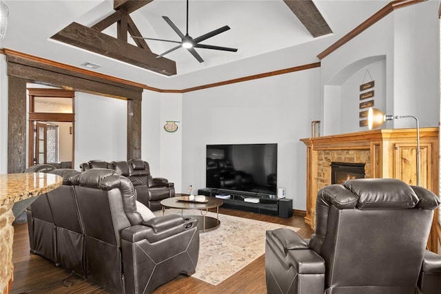 living room with ceiling fan, a stone fireplace, vaulted ceiling with beams, and dark hardwood / wood-style flooring