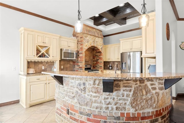 kitchen featuring tasteful backsplash, pendant lighting, cream cabinetry, and appliances with stainless steel finishes