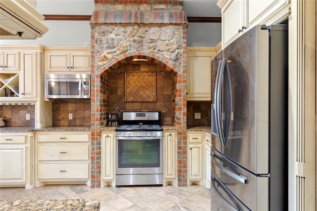 kitchen featuring crown molding, appliances with stainless steel finishes, cream cabinets, and decorative backsplash