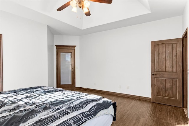 bedroom with a raised ceiling, dark hardwood / wood-style flooring, and ceiling fan