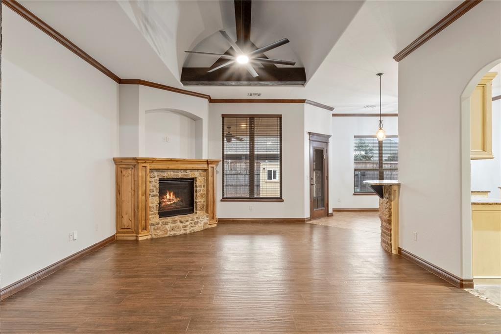 6501 Bent Wood Dr, Oklahoma City, OK 73169 - unfurnished living room with arched walkways, a stone fireplace, ceiling fan, and dark wood-type flooring