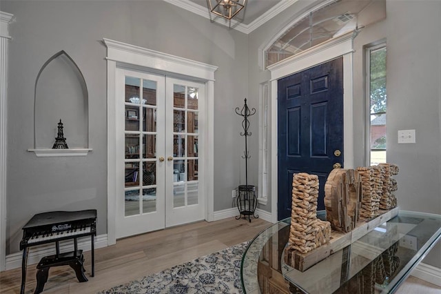 foyer entrance featuring hardwood / wood-style floors, a notable chandelier, crown molding, and french doors