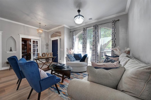 living room featuring crown molding, a chandelier, and light wood-type flooring