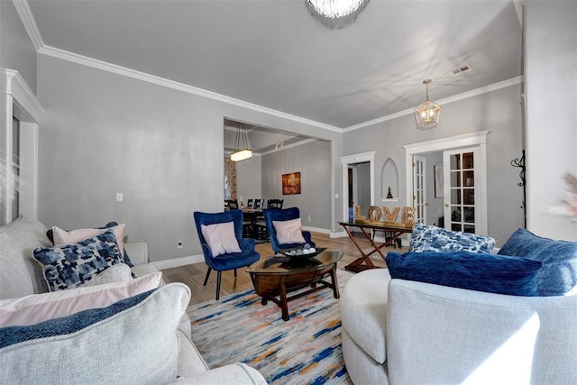 living room with light wood-type flooring, an inviting chandelier, and crown molding