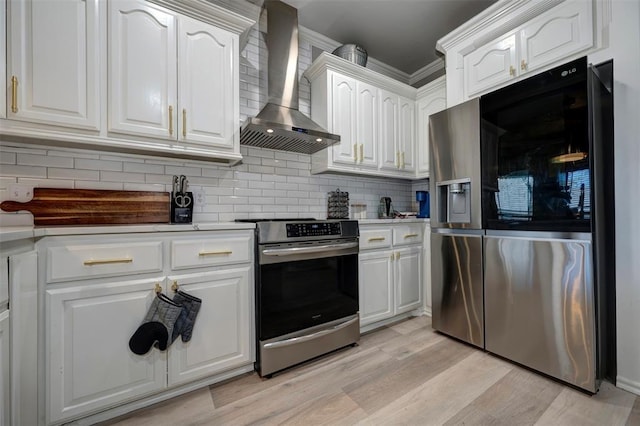 kitchen with wall chimney exhaust hood, stainless steel appliances, tasteful backsplash, light hardwood / wood-style floors, and white cabinets