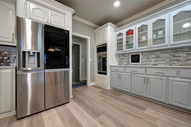 kitchen with appliances with stainless steel finishes, backsplash, white cabinetry, and ornamental molding