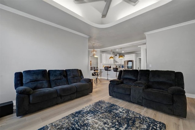 living room featuring light hardwood / wood-style floors, ceiling fan, and ornamental molding