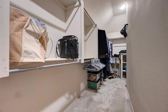 spacious closet featuring light colored carpet and vaulted ceiling