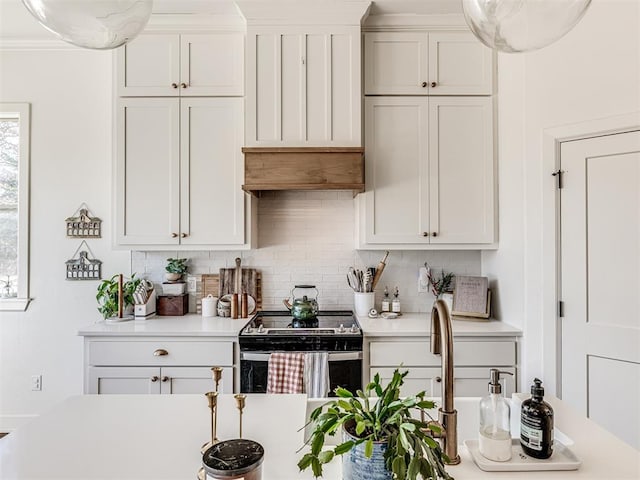 kitchen with electric stove, tasteful backsplash, and white cabinets