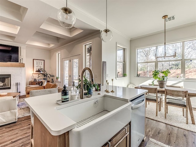 kitchen with a kitchen island with sink, sink, decorative light fixtures, and ornamental molding