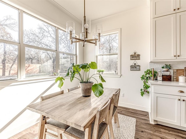 dining area with crown molding, dark wood-type flooring, and an inviting chandelier