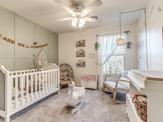 carpeted bedroom with a nursery area and ceiling fan