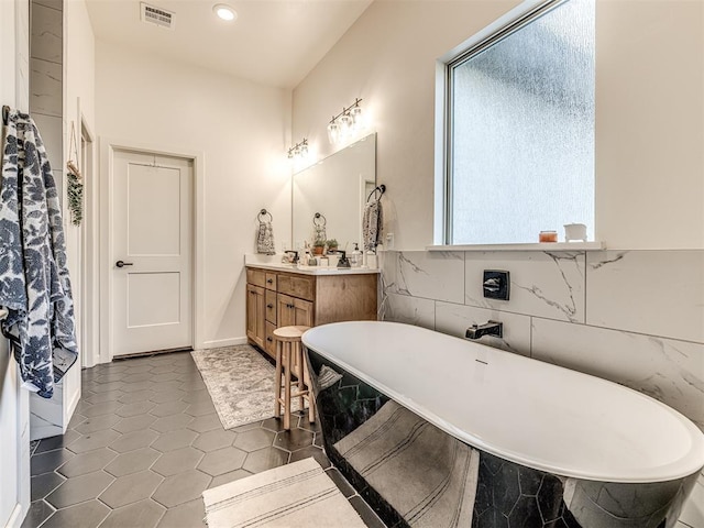 bathroom with vanity, tile patterned flooring, tile walls, and a washtub