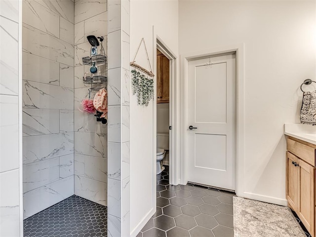 bathroom with vanity, tiled shower, tile patterned floors, and toilet