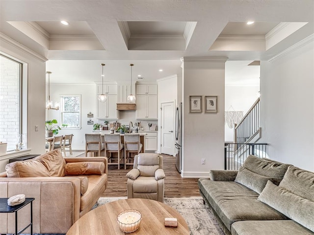 living room featuring coffered ceiling, crown molding, light hardwood / wood-style flooring, a notable chandelier, and beam ceiling