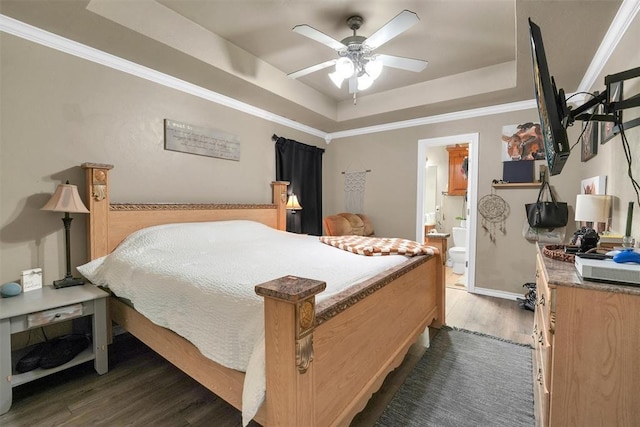 bedroom featuring connected bathroom, ceiling fan, a raised ceiling, dark hardwood / wood-style flooring, and crown molding