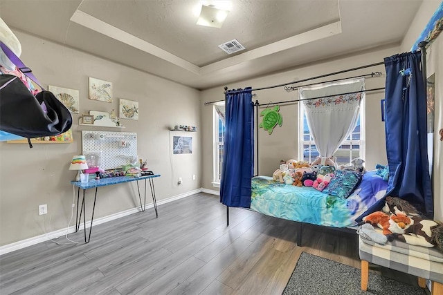 bedroom featuring a raised ceiling and hardwood / wood-style flooring