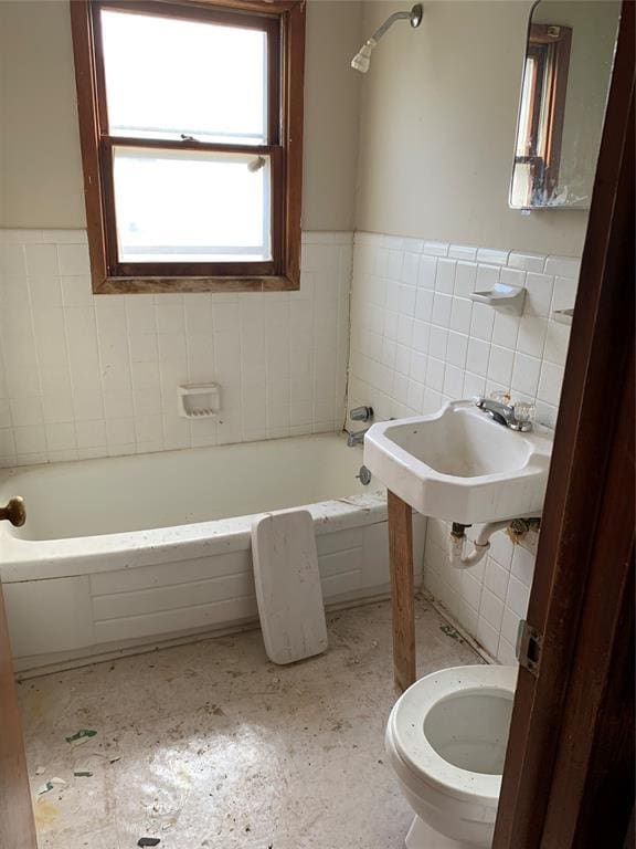 bathroom featuring toilet, tile walls, a tub, and sink