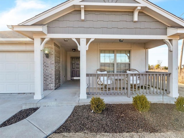 view of exterior entry featuring covered porch, brick siding, and an attached garage