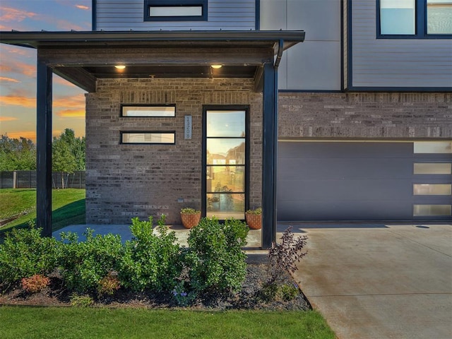 exterior entry at dusk featuring a garage